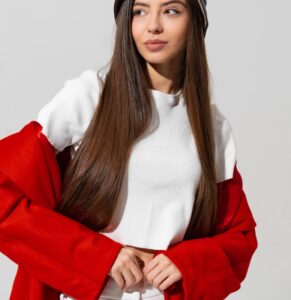 pretty girl black hat red coat raised hands holding cap studio white wall 1 min