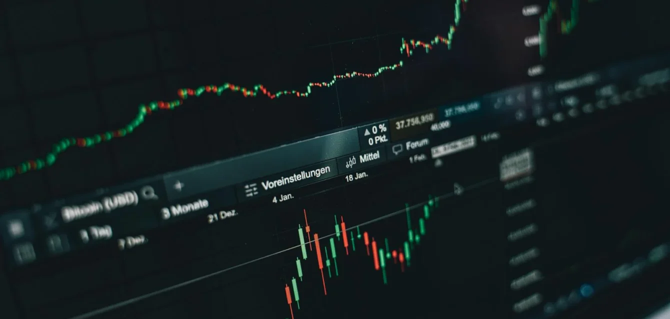 Photo by Alesia Kozik Close-up of a digital market analysis display showing Bitcoin and cryptocurrency price trends.