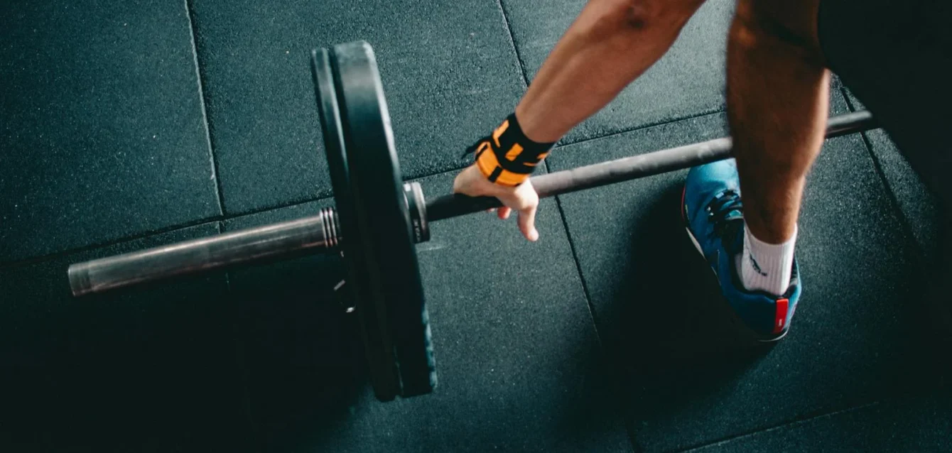Close-up of a person lifting a barbell in an indoor gym, focusing on strength training.