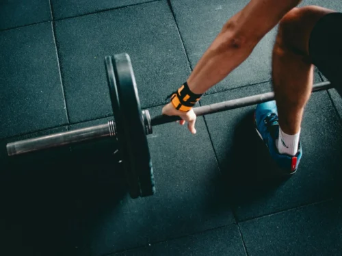 Close-up of a person lifting a barbell in an indoor gym, focusing on strength training.