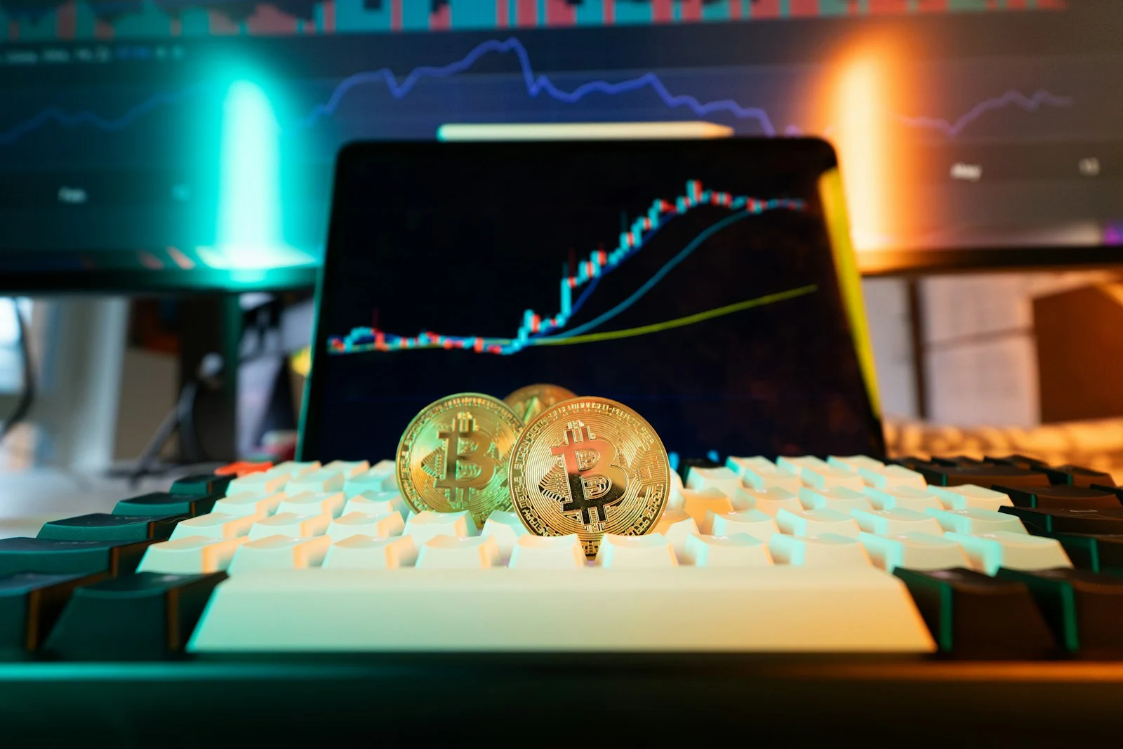 Photo by Jakub Żerdzicki Bitcoin coins rest on a keyboard with stock charts.