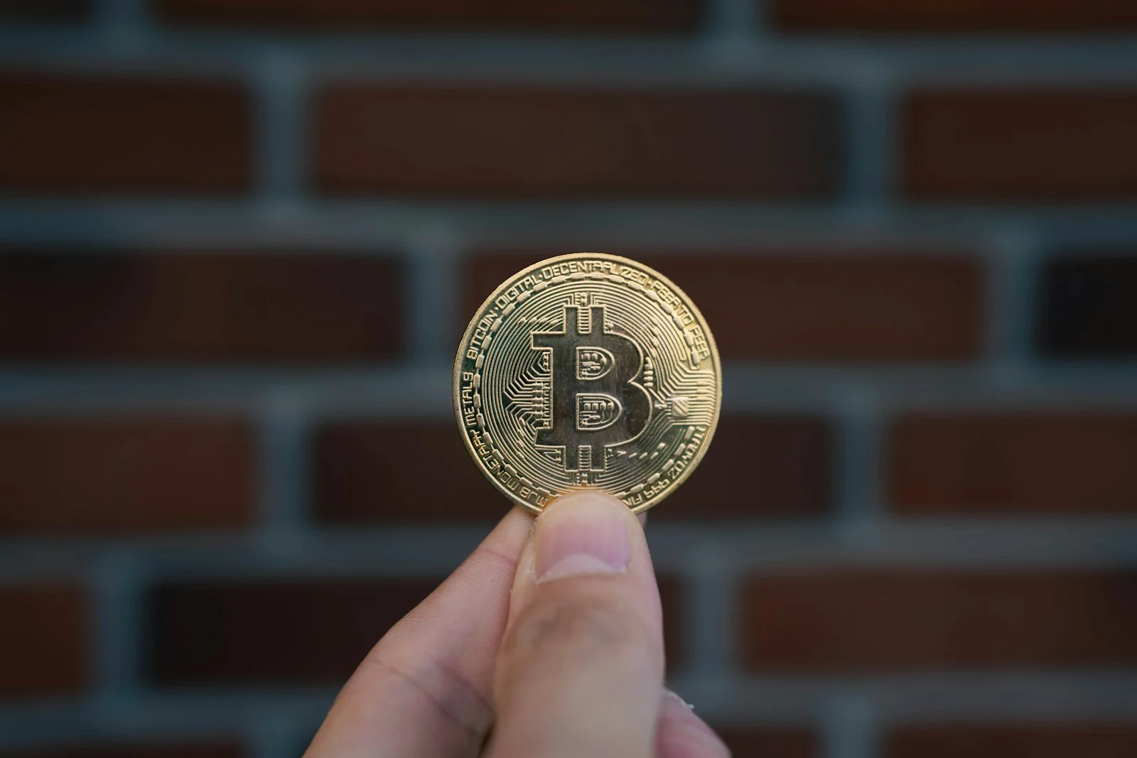 Photo by Valentin A hand is holding a bitcoin coin.