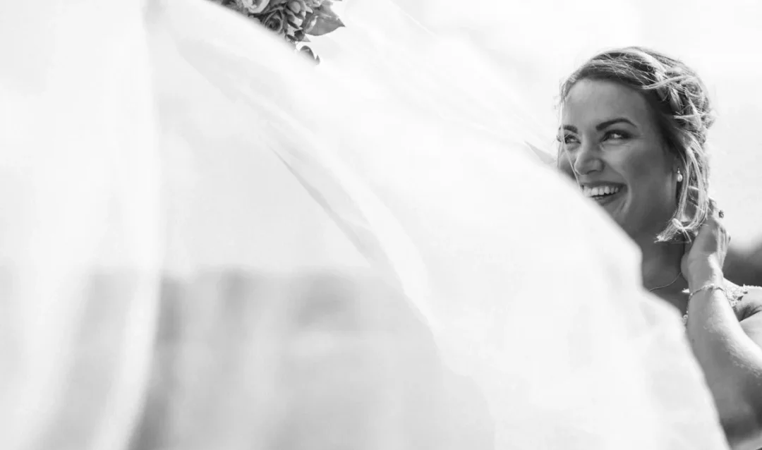 Photo by Jeppe Mønster a woman in a wedding dress holding a veil