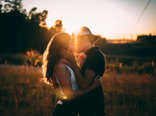 man and woman kissing during sunset