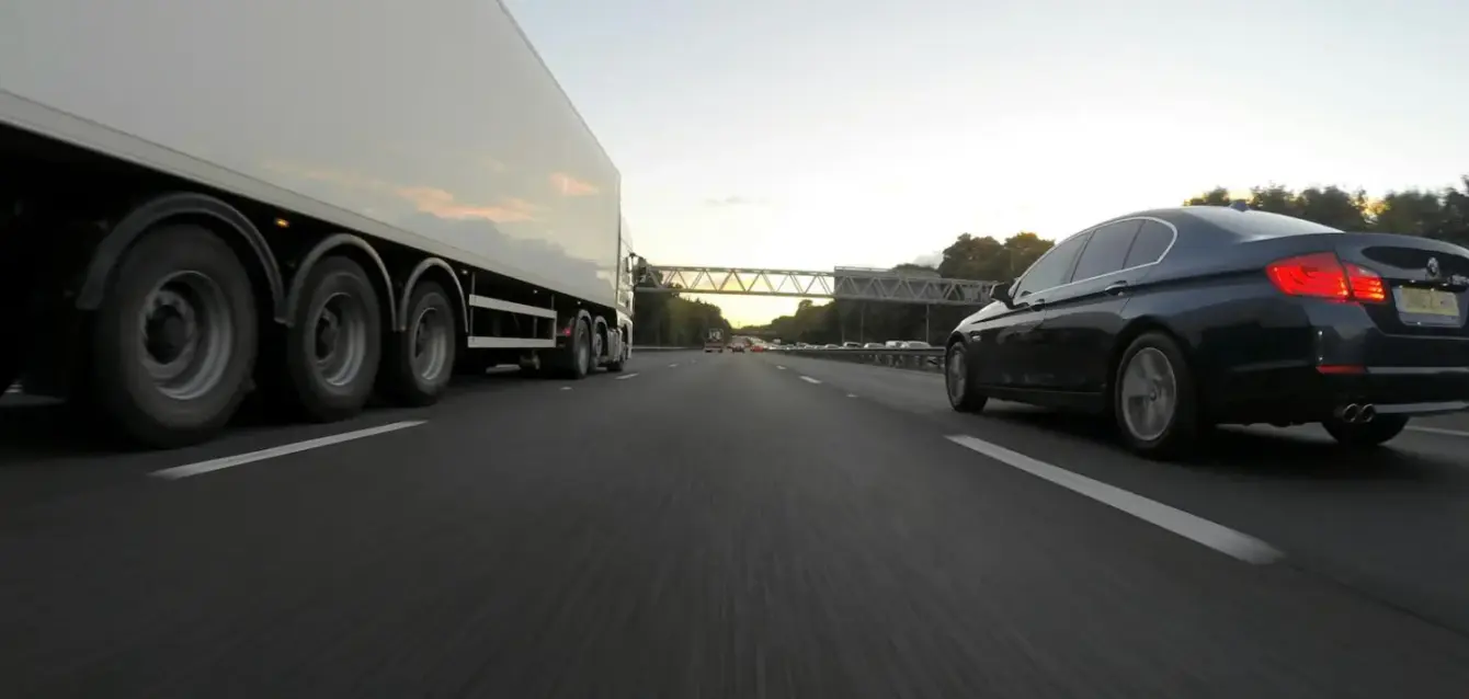 Cars and a truck speed along a highway under the clear sky, showcasing transportation dynamics.
