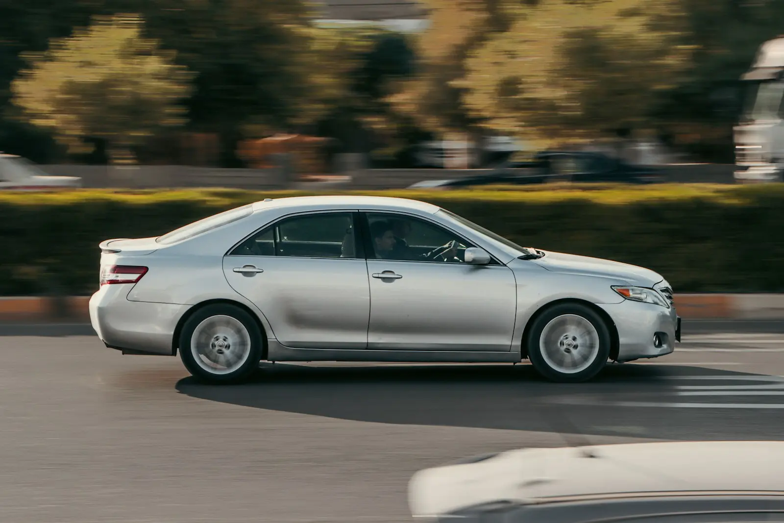 a silver car driving on a road